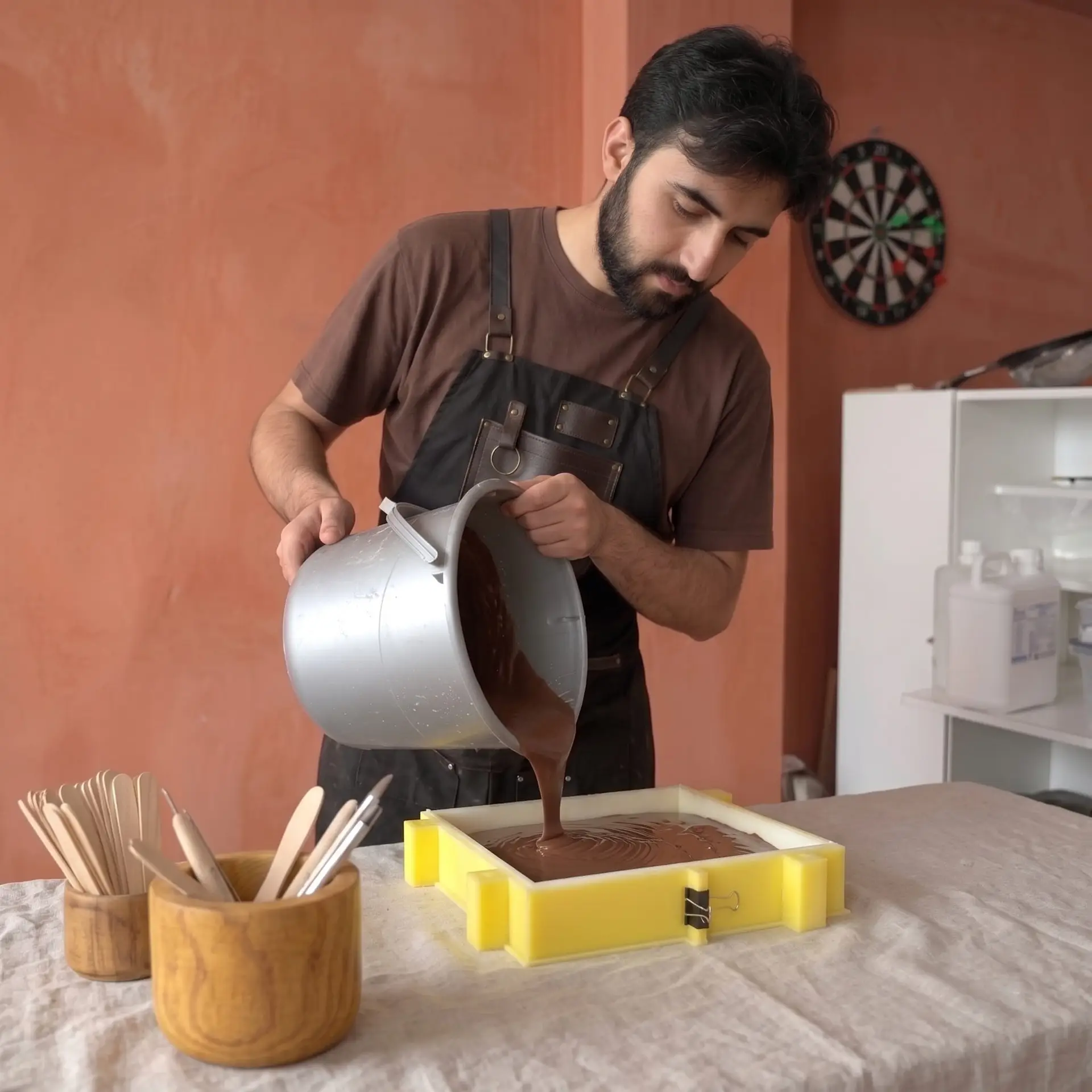 Girift kurucusu Ali'nin brütalist beton döküm atölyesinde, deri zanaatkar önlüğü ile kalıplar önünde verdiği sanatsal portre.
